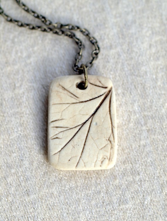 Earthling - a sweet porcelain pendant with impression of a small plant.