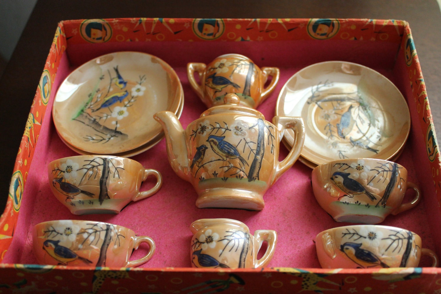 a vintage children's tea set with artistic detailing of birds