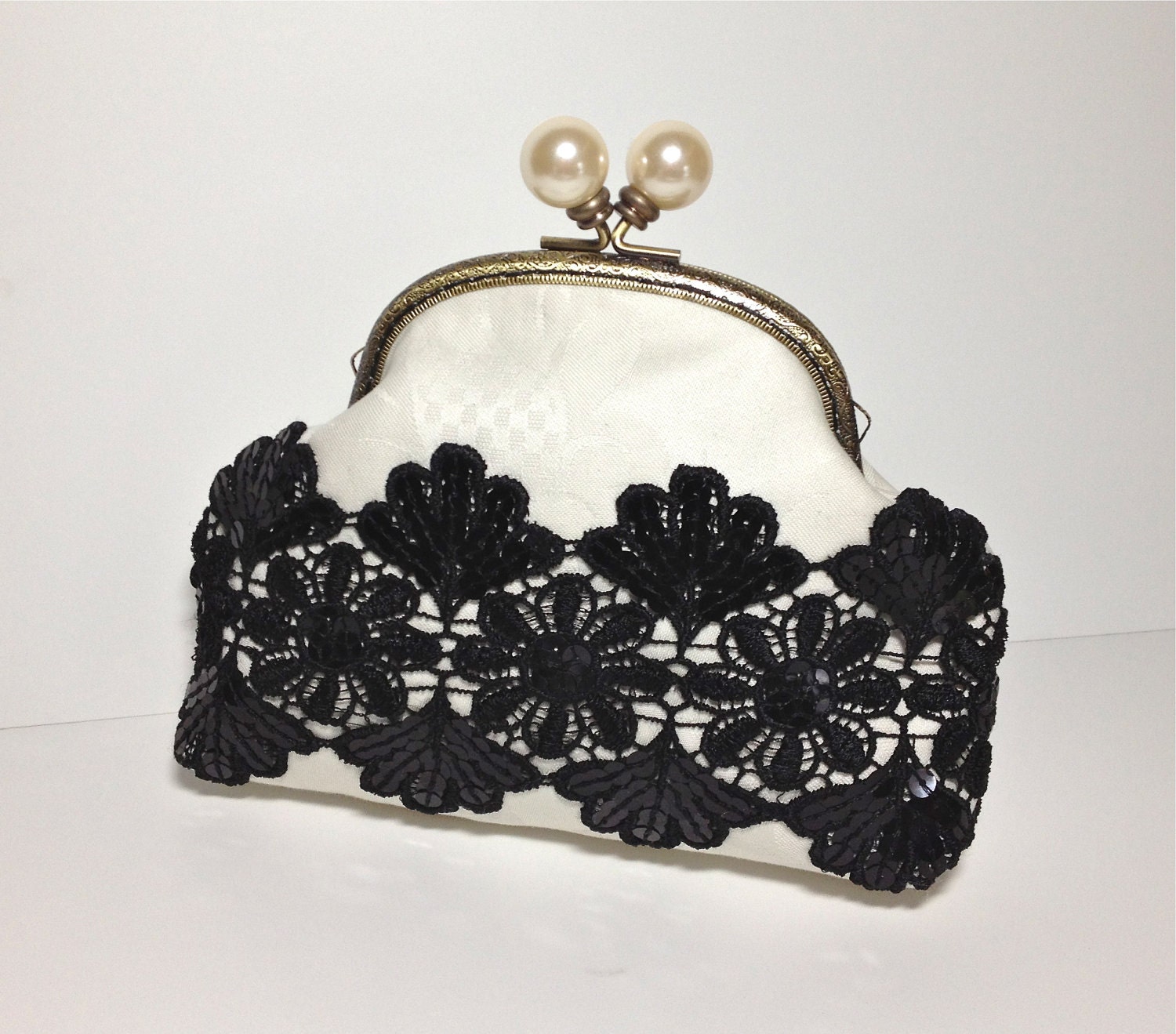 Cream-colored clutch with pearl enclosure and black lace