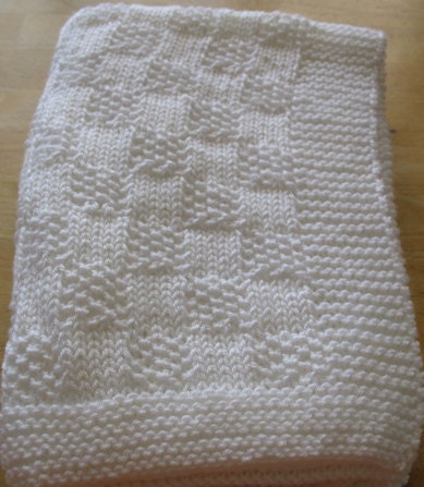 White hand knitted baby blanket in a checkerboard pattern for