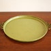 Olive green round serving tray with Asian handles and brass accents