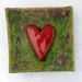 Red ceramic heart wall tile with green mossy lichen texture background Valentine