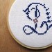 blue and purple letter D cross stitch sampler.