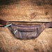 Distressed purple handcrafted leather (cowhide) fanny pack - hand cut, sewn, and riveted - Electric purple zips, teal pull tabs.