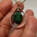 Beadwork necklace with a spinning forest of seed beads suspended in a silver teardrop frame
