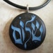 Hebrew - Shalom - Peace hand carved on a black pearl background. Pendant comes with a 3mm leather necklace