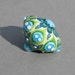 Handmade lampwork glass bead in different shades of green, blue and white by Flamejewels.