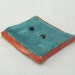 deep turquoise button, hand-shaped ceramic with swirls and red edges