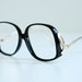 oversize black plastic glasses, 70s bugeye eyeglasses, gold metal butterfly temples, chic