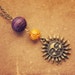 RESERVED earthlight. a purple and orange beaded sun pendant.