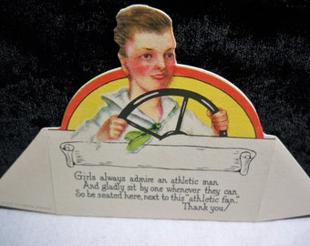 Wonderful art deco 1920's die cut place card young man wearing a sailors shirt driving a car unused