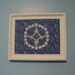 Framed blue and white wall art featuring hand tatted flowers and butterflies