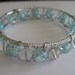 Wire wrapped silver bangle bracelet with light blue frosted and clear beads