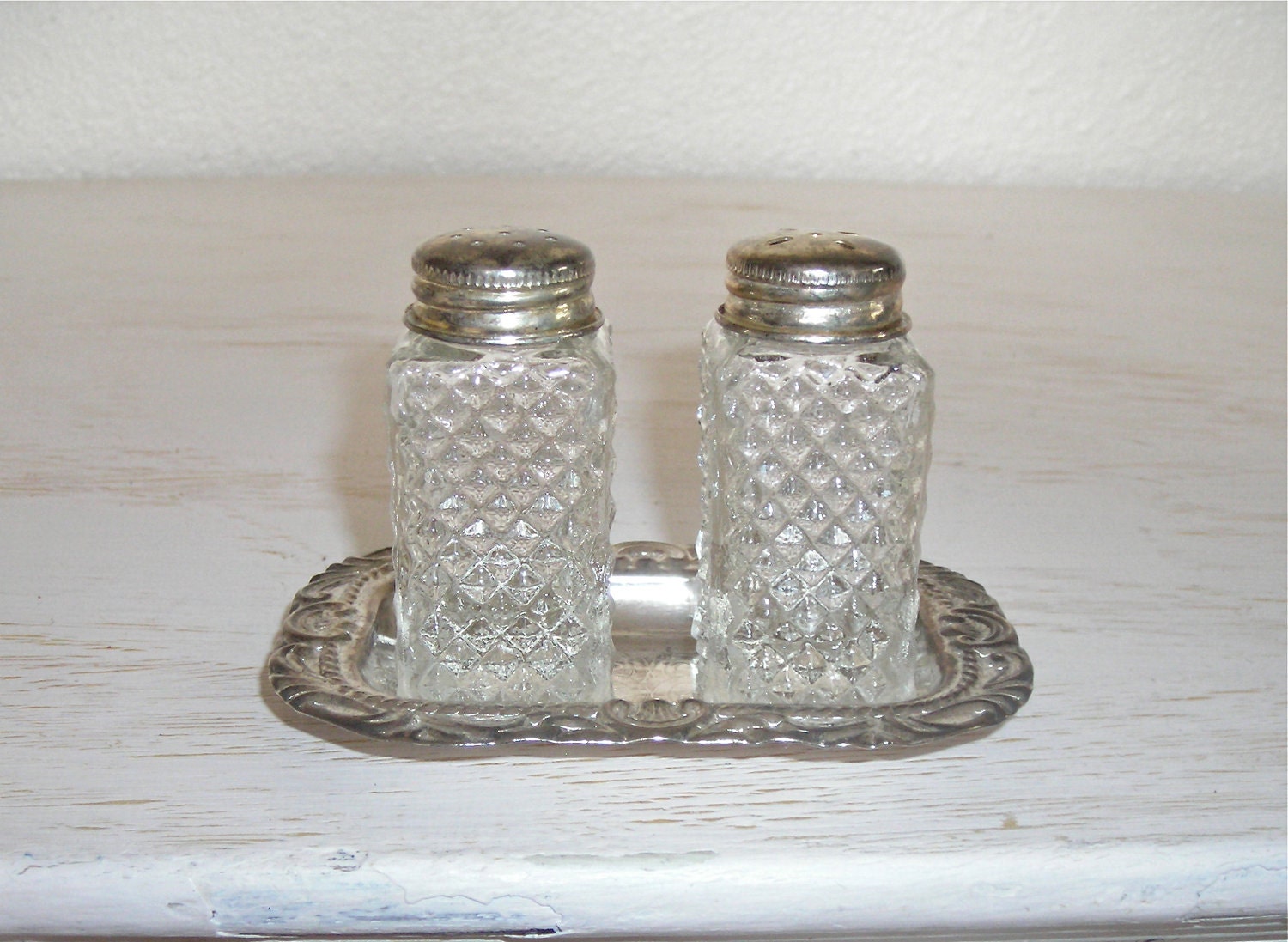 vintage pressed glass salt and pepper shakers on ornate silver