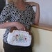 Vintage white purse with hand stitched crewel flowers. Wooden handle.
