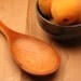 Wooden spoon for stirring with tasting spoon carved onto the handle made from cherry wood
