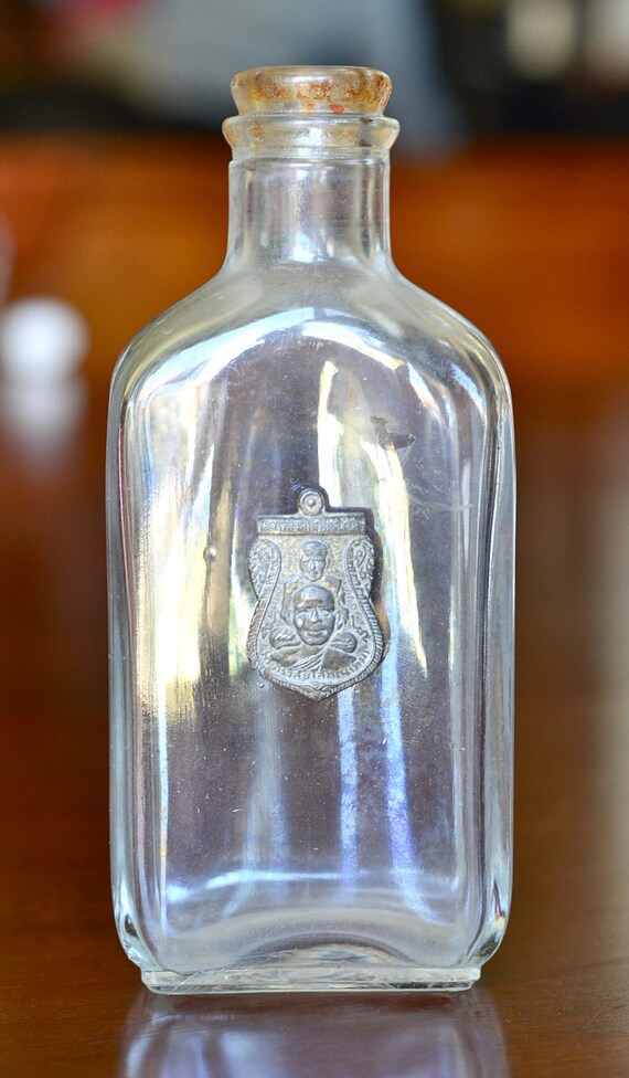 Vintage glass medicine bottle with a Buddha by 180degreesvintage