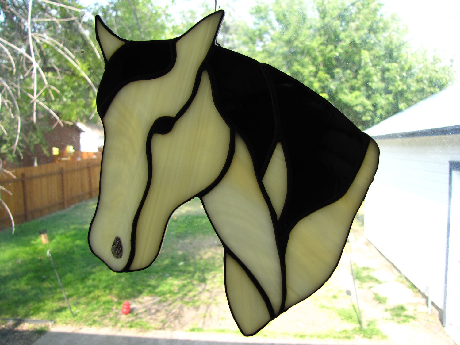 Stained glass suncatcher of tan horse with a black mane