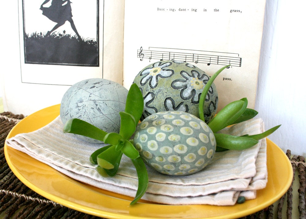 Three decorative ceramic spheres in pale green yellow and
