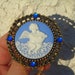 Angel-cupid playing harp 3-D cameo brooch white on blue powder color with moonstone-like heart charm