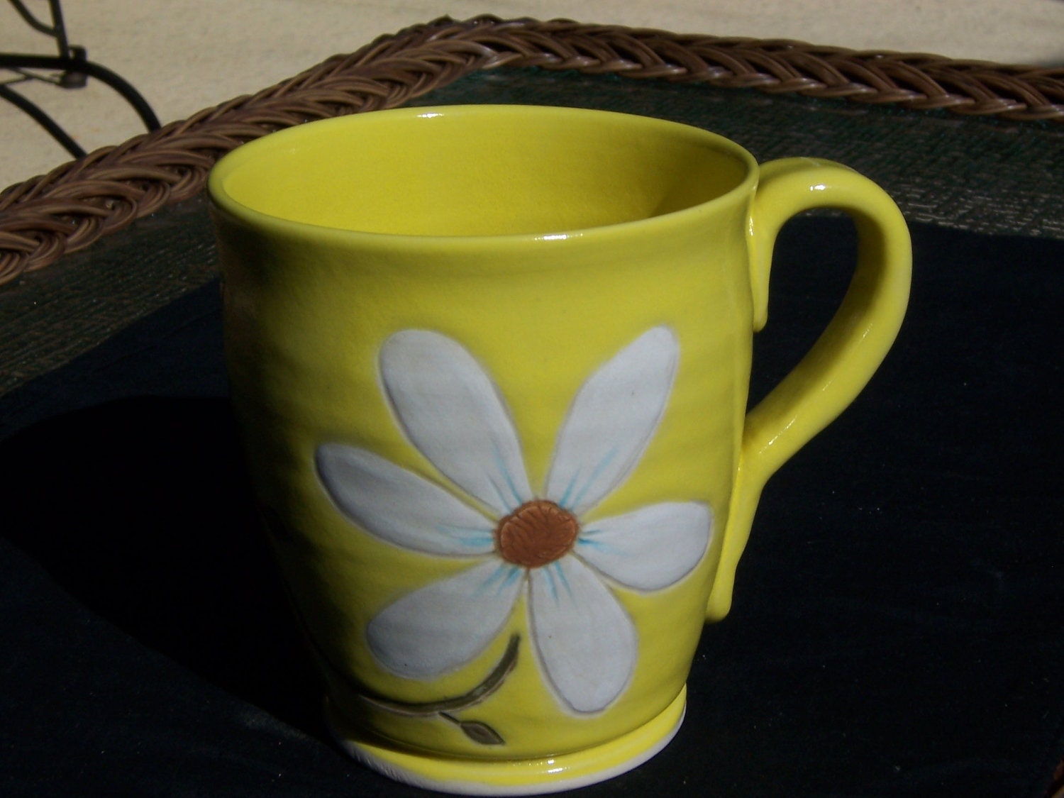 Stoneware coffee mug in bright yellow with large white daisy