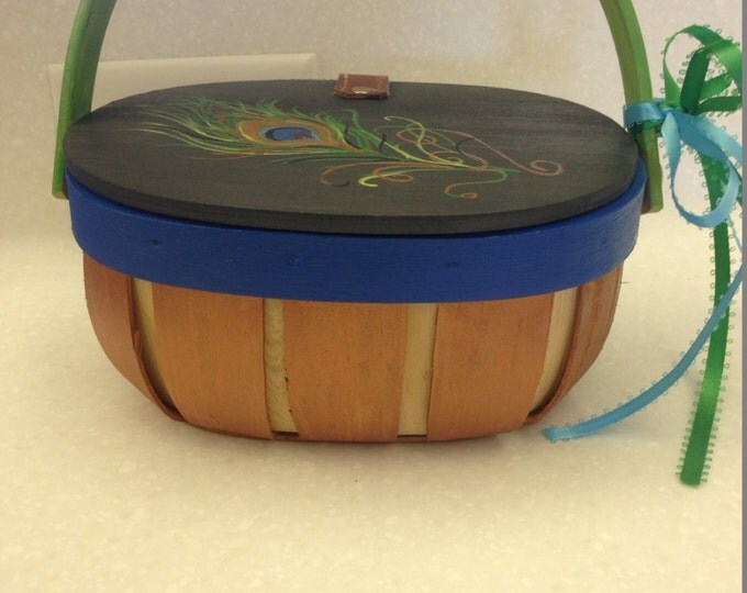 Wood Basket with Solid Wood Lid has leather hinge to keep it attached. Decorated with a big, beautiful peacock feather.