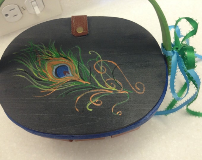 Wood Basket with Solid Wood Lid has leather hinge to keep it attached. Decorated with a big, beautiful peacock feather.