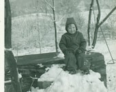 Little Farm Boy Playing in the Snow Twine Rope Around Waist Snow Suit Sitting on Log1950s Black White Photo Photograph