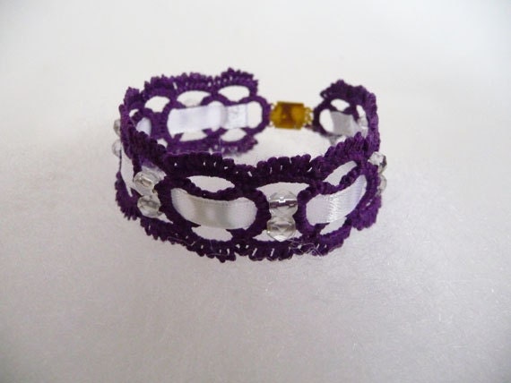 Handcrafted purple bracelet with beads and ribbon.
