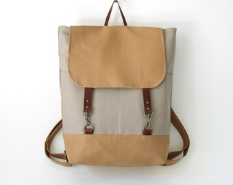 Gray canvas, camel flap Backpack , laptop bag, diaper bag, travel bag. 2 front pockets. 7 inside pockets. Waterproof poly lining available