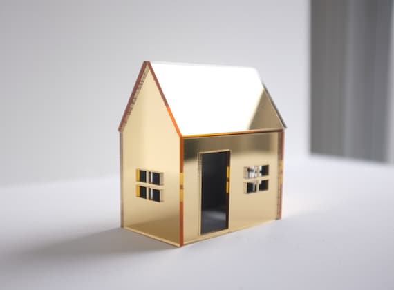 Golden miniature house structure in mirrored acrylic