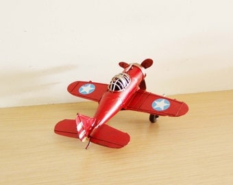 Red metal aeroplane, retro collectible toy plane with partly open cockpit and moving propeller, vintage airplane miniature, mid nineties