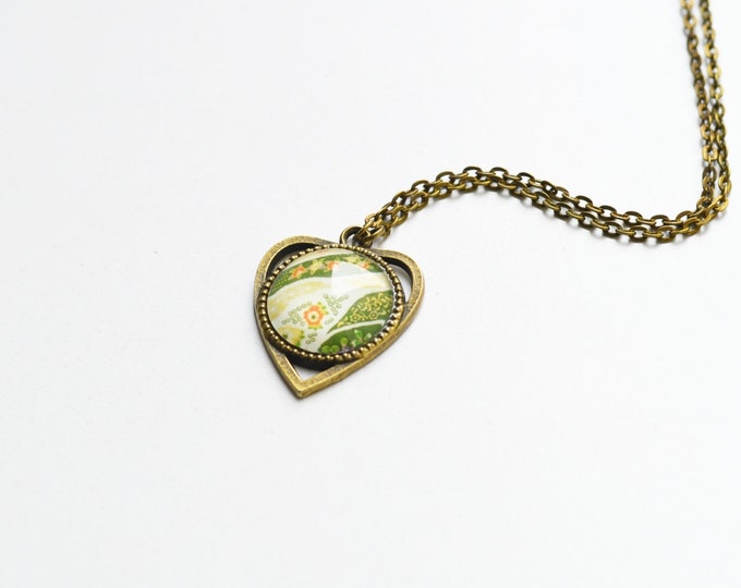 FLORAL MOTIFS The pendant is heart-shaped metal brass with pictures of flowers under glass