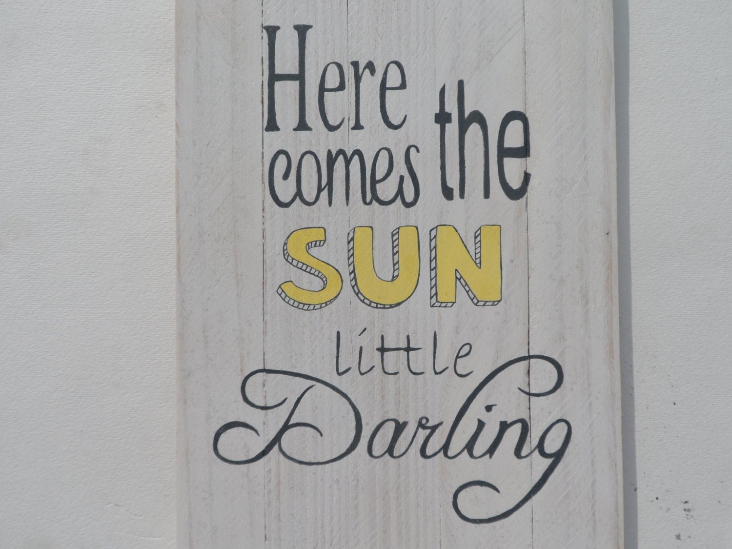 Here comes the sun little darling quote on a wooden sign. A