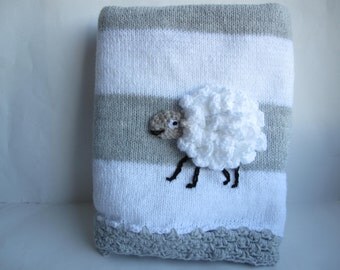 Grey and white knitted baby blanket with a crochet sheep