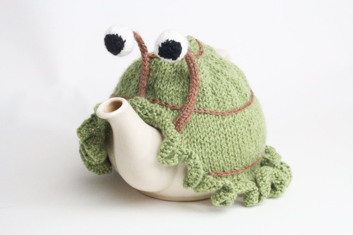 Knitted green snail tea cosy with frilly bottom. Washable fits