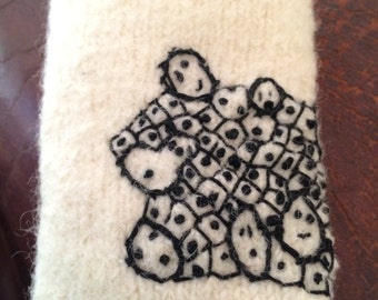 Wool iPhone case. Cream with pebble people in black embroidery. Hand knitted then felted and added a black fleece liner.