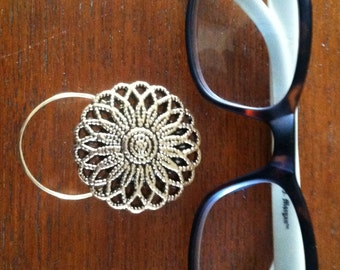 The mattie gold tone flower magnetic eyeglass holder is a pretty and practical way to keep track of your glasses.