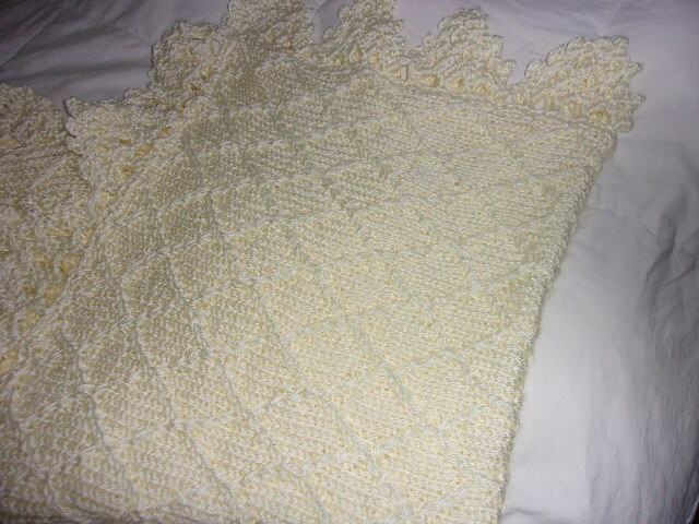 Hand knit baby blanket in diamond pattern with crocheted