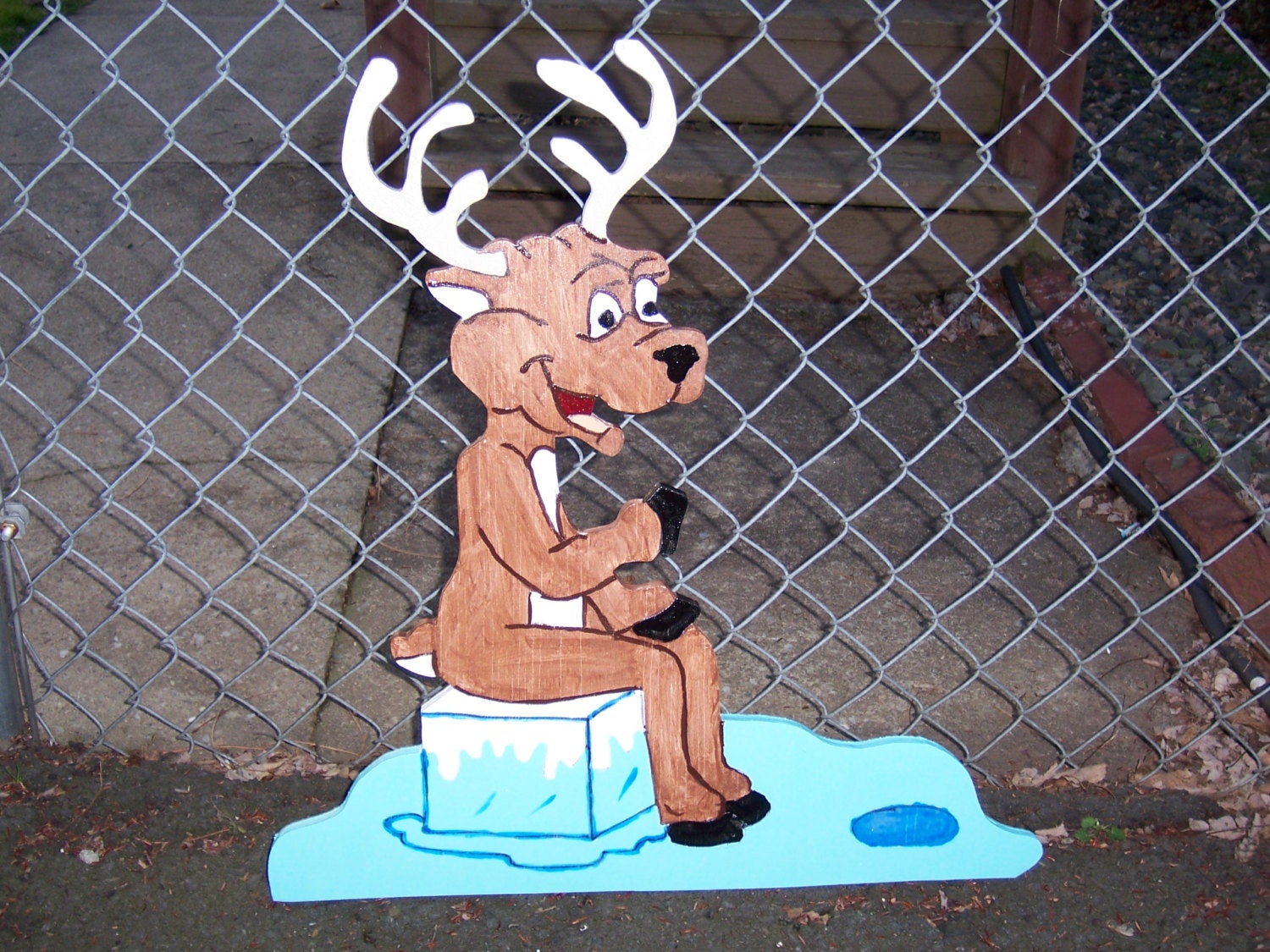 Handmade custom painted wooden reindeer sitting on the ice for your yard