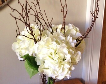 Stunning artificial realistic hydrangea floral arrangements with twigs set in still water, available in either cream or amethyst .