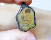 Clever  beach glass charm with solder and ephemera.