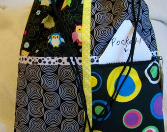 owls in brights with circles in colors and black and white on a yellow ripstop nylon drawstring backpack with front zipper pocket
