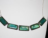 Lustrous teal green enameled necklace.  The copper base reflects light through transparent teal enamel.  Sterling silver chain & clasp.