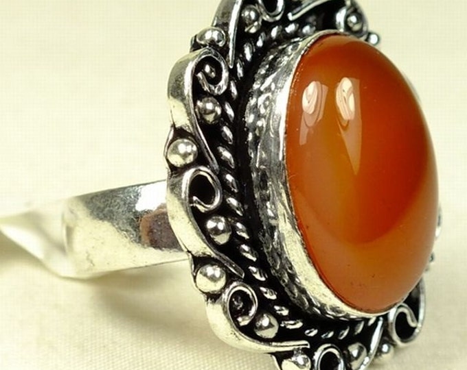 Storewide 25% Off SALE ladies cocktail ring features center 'Red Onyx' polished stone set in scrolling white metal setting.