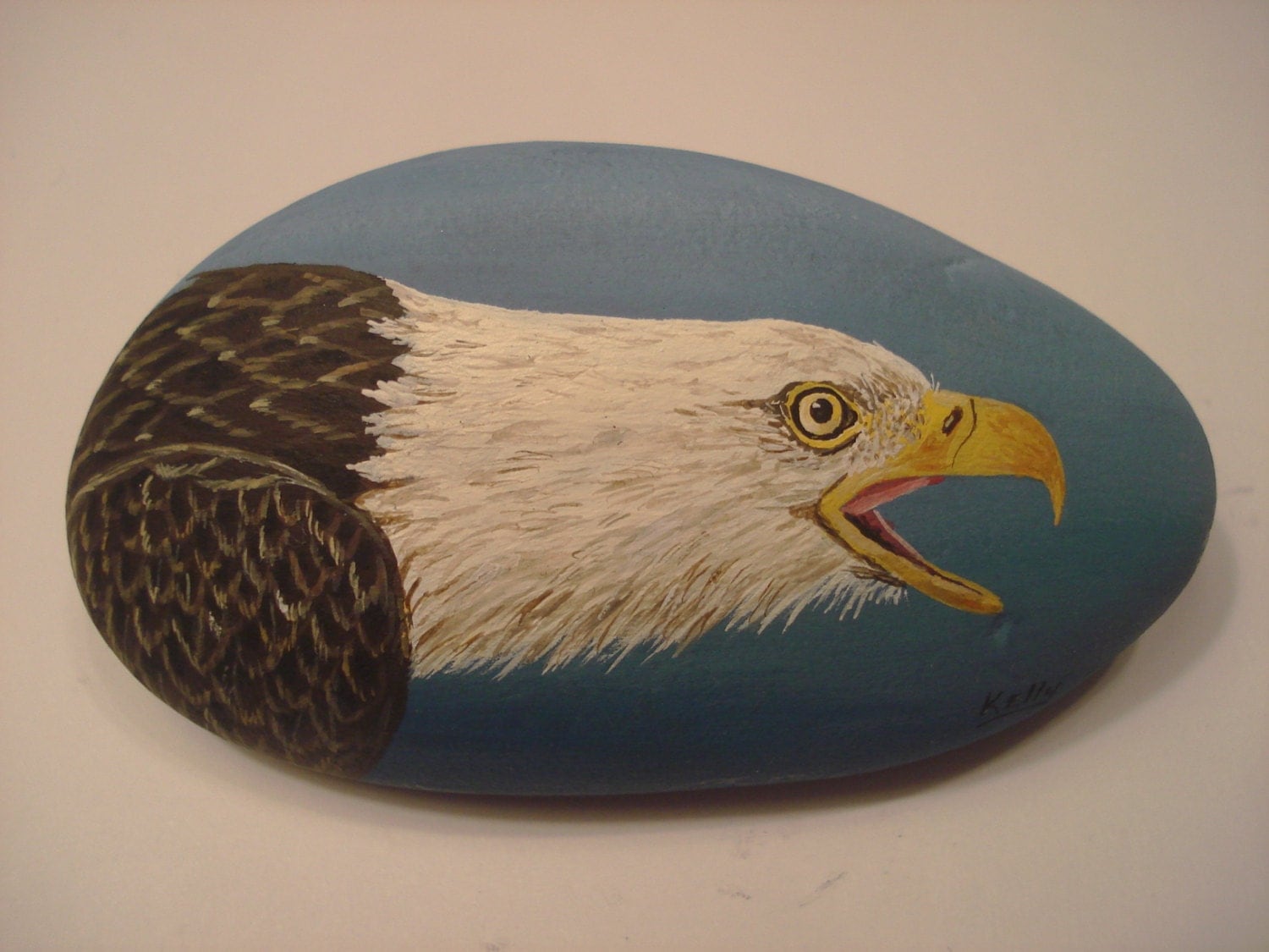 Bald Eagle portrait hand painted on a rock by Ann Kelly.