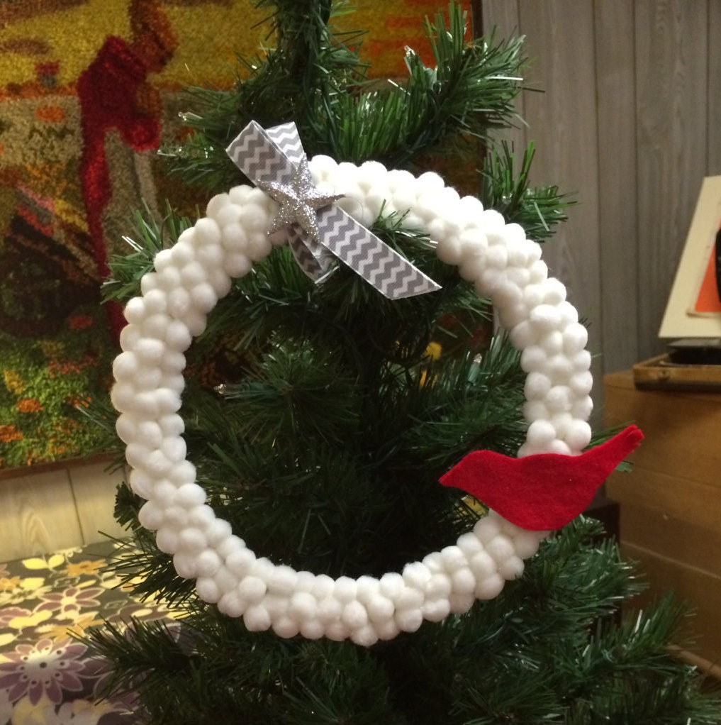 Mini Christmas wreath. Tiny balls of cotton cover an embroidary hoop. Little red felt bird attached and topped with chevron ribbon and star