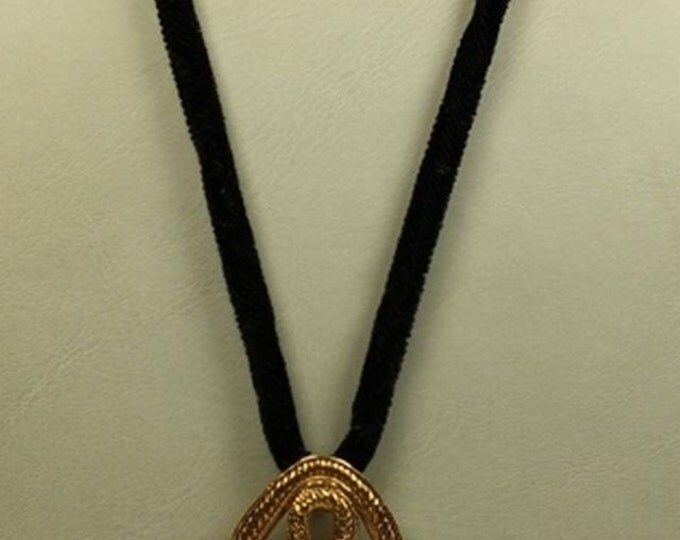 Storewide 25% Off SALE Striking DAUPLAISE designer necklace featuring a large ornately designed goldtone pendant resting on a black velvet r