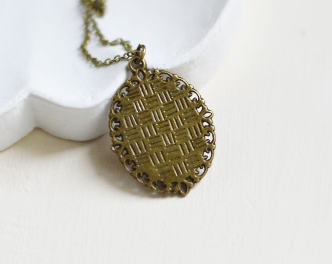 Weightless // Oval pendant metal brass with a picture of the feather under glass
