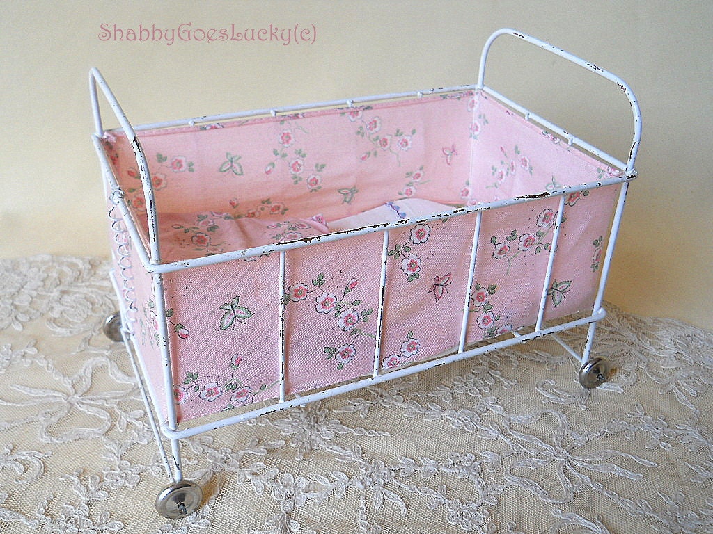 Small vintage 1950s metal doll bed on tin wheels with bedding